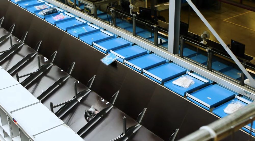 Blauwe sorteerbakken op een transportband in een distributiecentrum