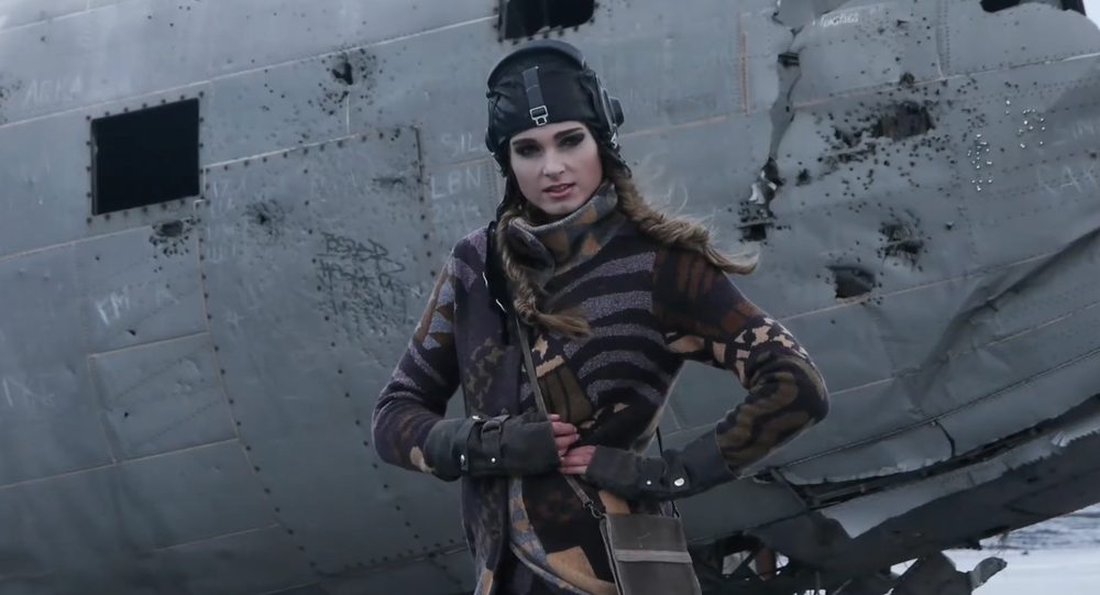 Model in gebreide kleding bij een vliegtuigwrak in de sneeuw